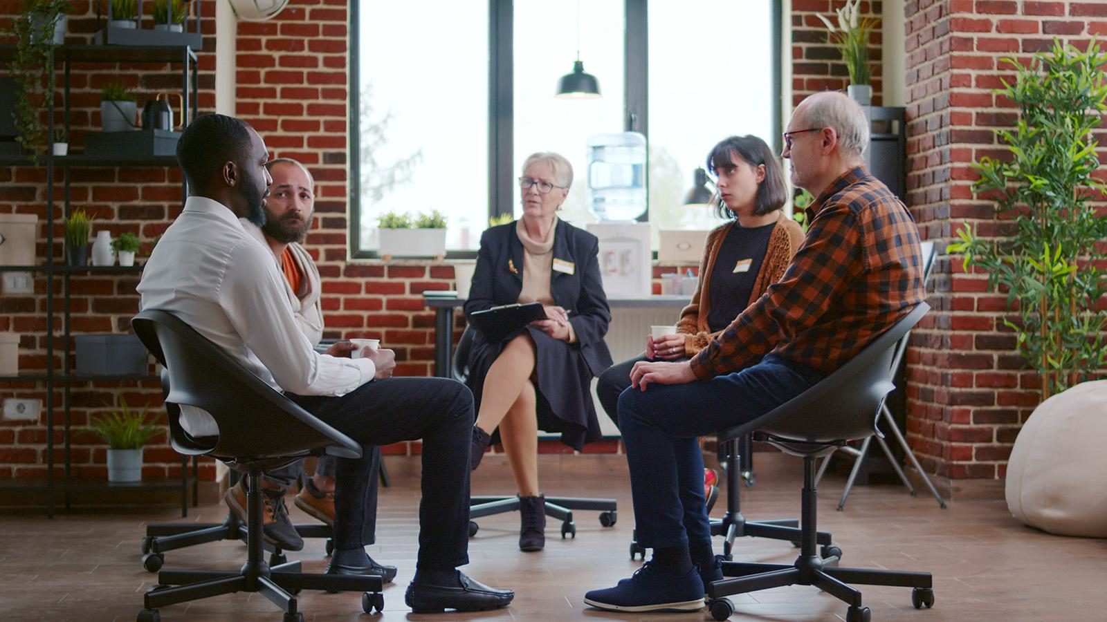 female psychotherapists talking to two male therapy patients